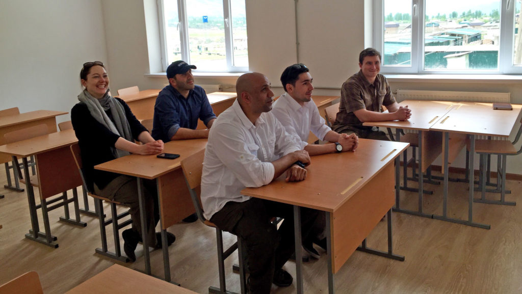 Zack along with two members of the civil affairs team, their interpreter and a U.S. Department of State official trying out the new school desks