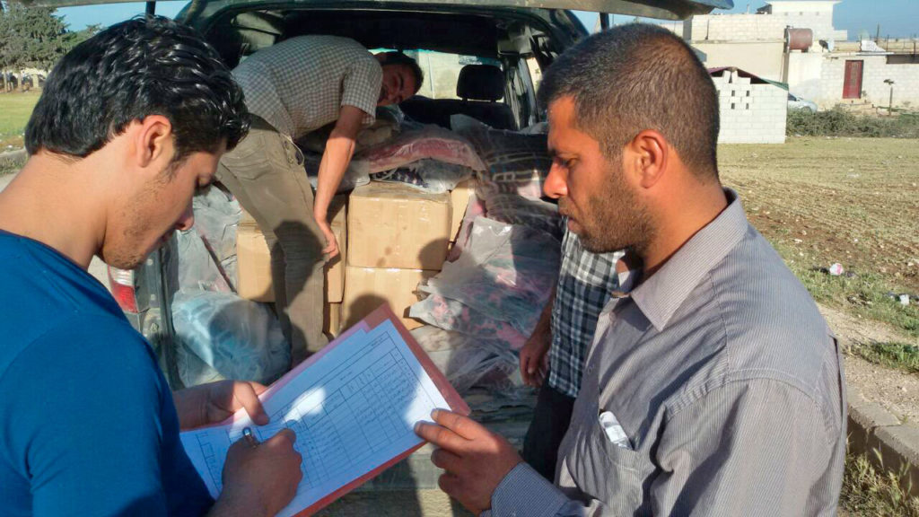 Representatives from the Aleppo Stabilization Committee distributing relief supplies to Syrian citizens 